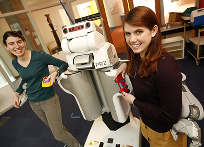 EECS PhD student Jennifer Barry and MIT EECS – Angle Undergraduate Research and Innovation Scholar Annie Holladay (right) pose with the robot for which they have developed algorithms to allow for more than just put and place functionality by the robot.