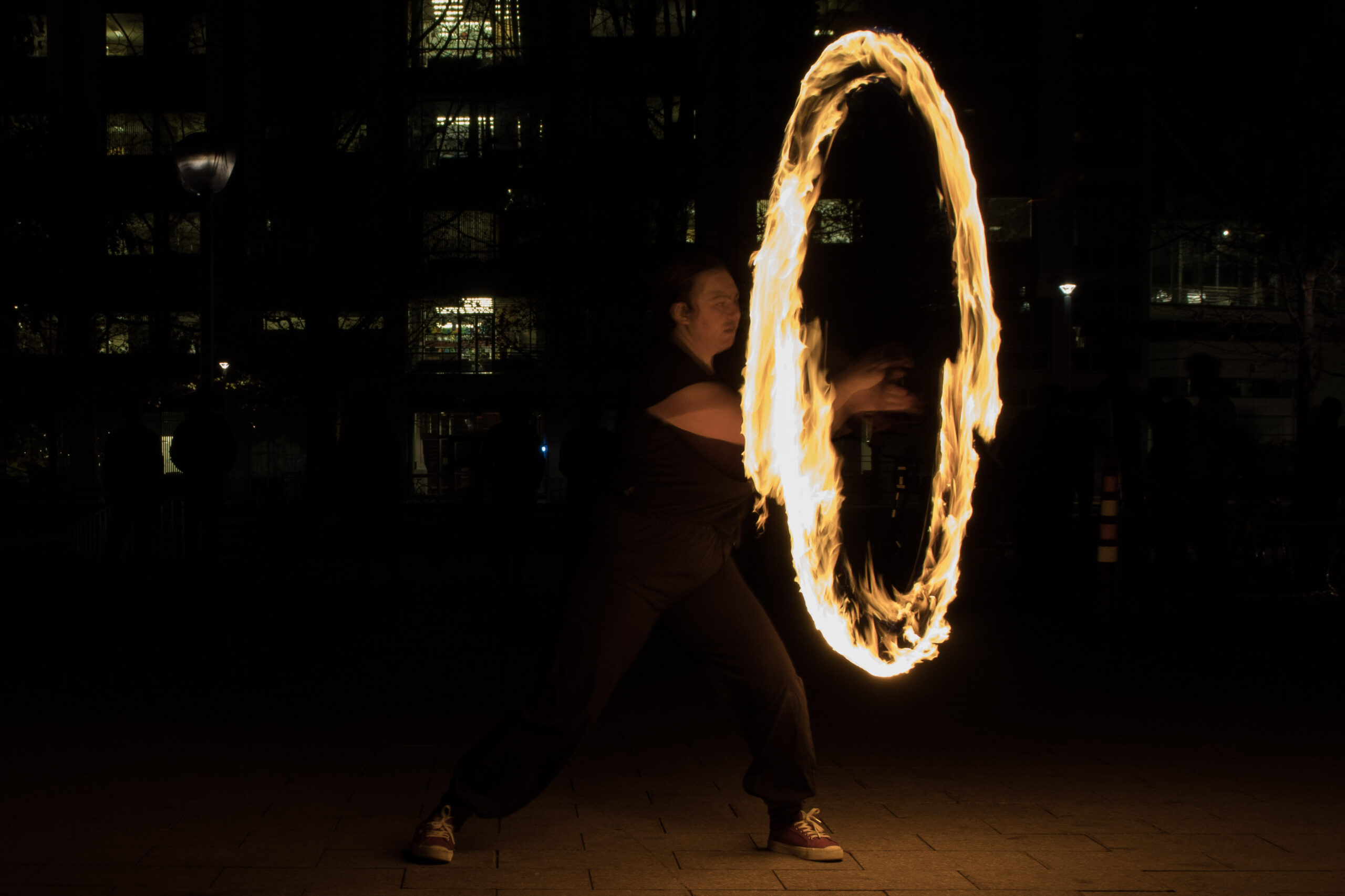 Ryn Moore spins fire in a simple loop, resulting in a bright circle as the camera captures several rotations of the quickly moving torch.