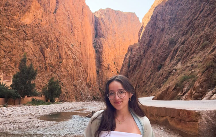 Student Isabel Duran stands in a partially dry riverbed inside a majestic canyon.
